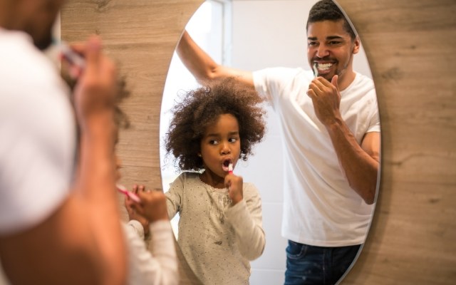Father and child brushing teeth together
