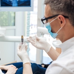 Dentist showing a dental implant model during initial consultation