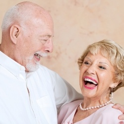 Man and woman smiling after dental implant restoration