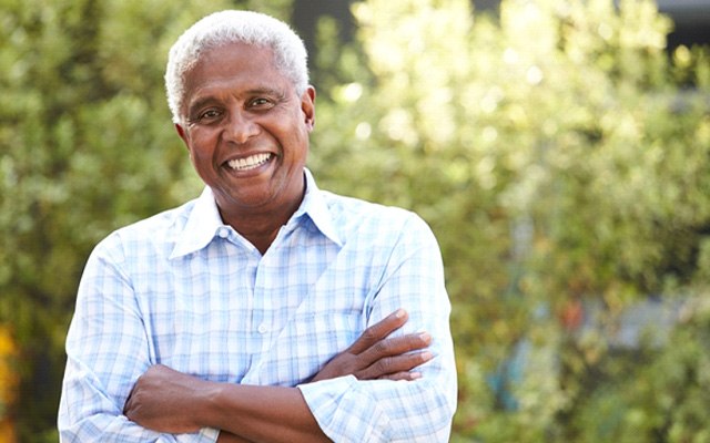 Man wearing blue shirt and smiling while wearing dentures