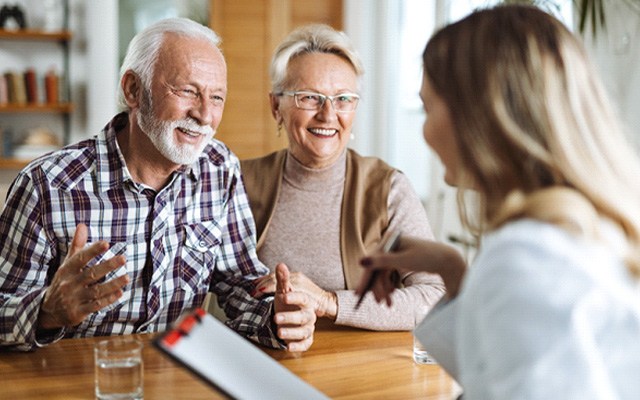 An older couple talking to a woman while wearing dentures