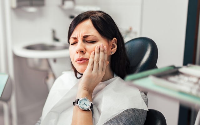 Wowman holding cheek in pain before emergency dentistry treatment