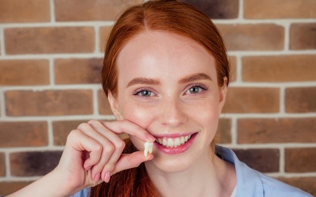 Woman holding a tooth after extraction