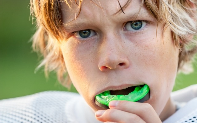 Youn person placing an athletic mouthguard