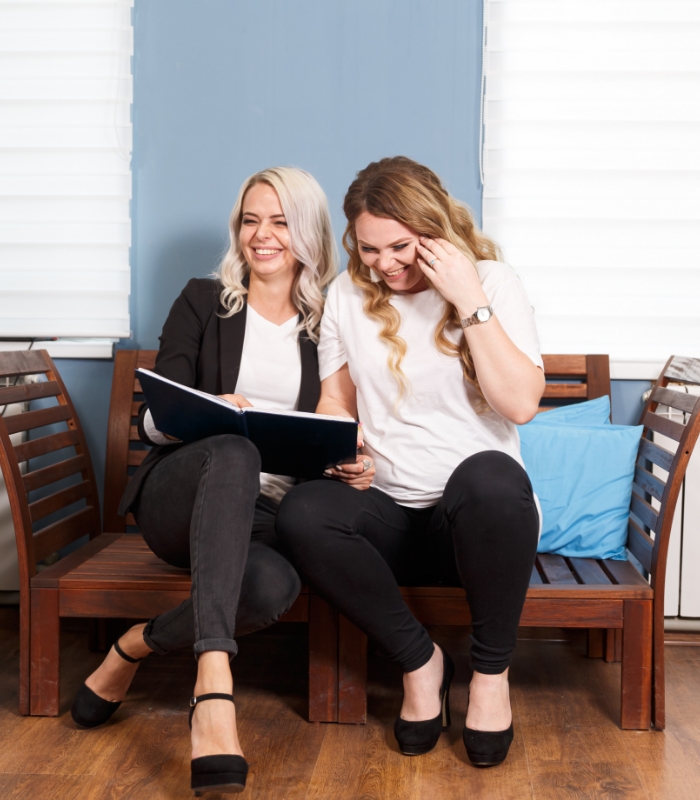 Two women sitting on a bench and laughing together