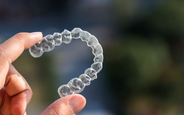 Hand holding an Invisalign tray