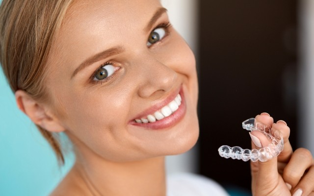 Smiling woman holding an Invisalign tray