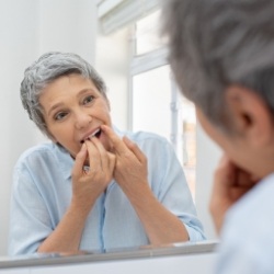 Senior woman flossing teeth