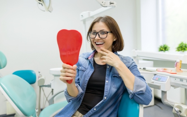 Woman looking at smile in mirror after makeover