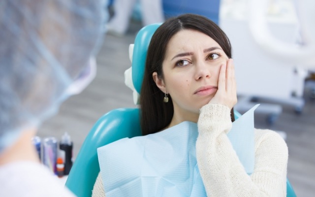 Woman holding cheek before wisdom tooth extraction
