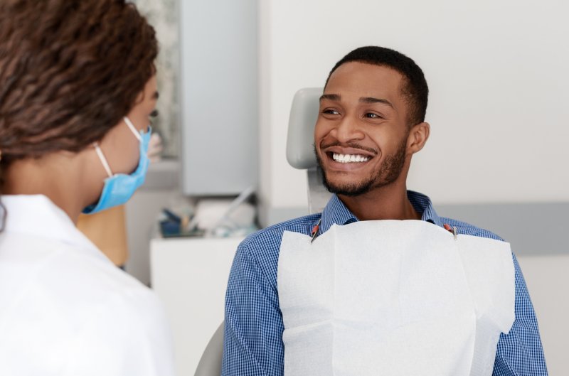 a male patient sitting and smiling while listening to his dentist talk about amalgam-free dentistry