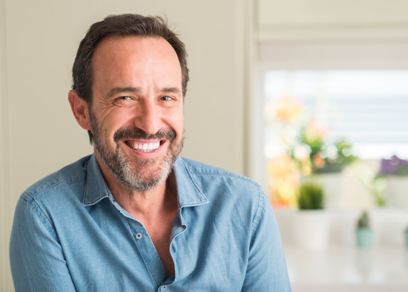 a middle-aged man wearing a button-down shirt and smiling after receiving treatment for gum disease