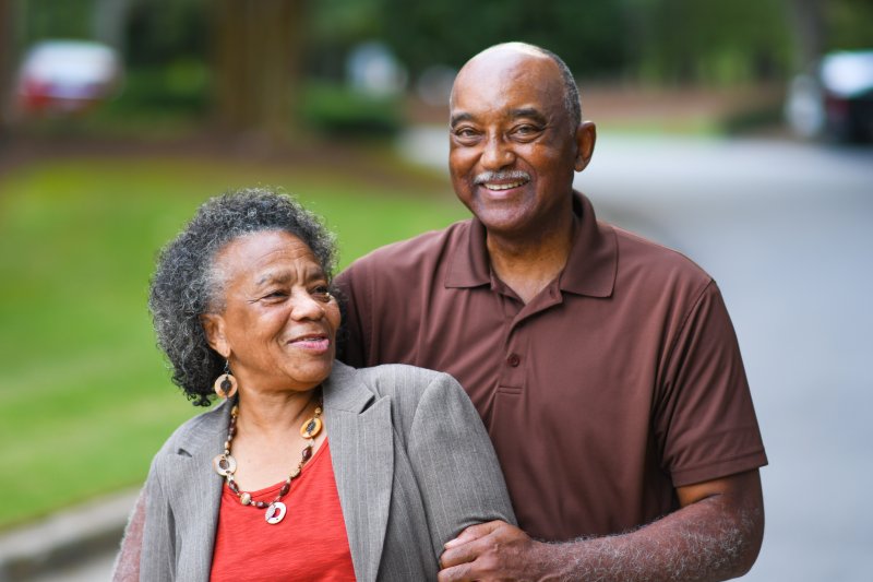 an older man and woman smiling and hugging while enjoying the outdoors