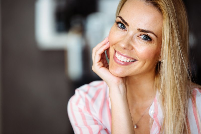 a young woman wearing a pink and white blouse smiles after gum recontouring in Chaska