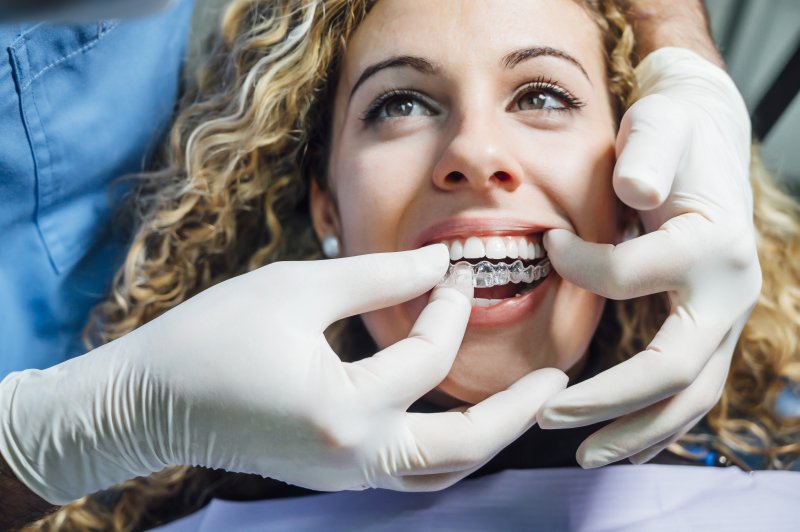a dentist fitting a female patient with her first set of Invisalign trays