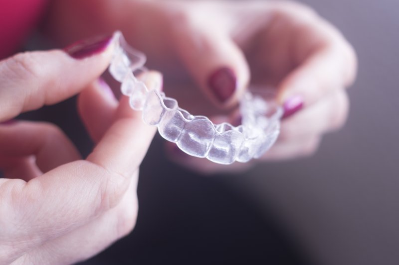 an up-close image of a person holding an Invisalign clear aligner 