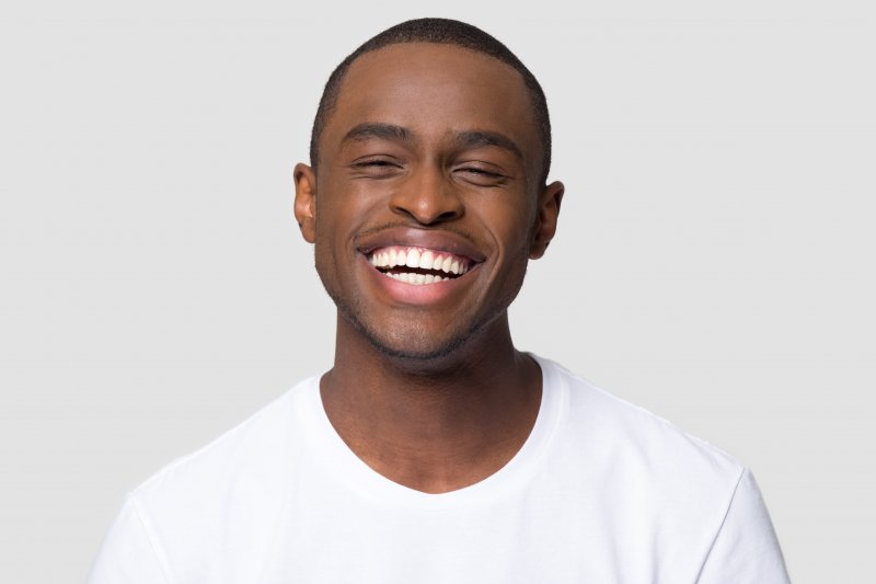 a young man wearing a white t-shirt and showing off his healthy, beautiful smile