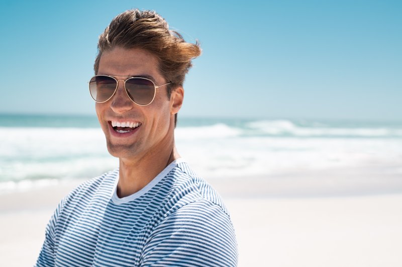 man smiling while standing on beach