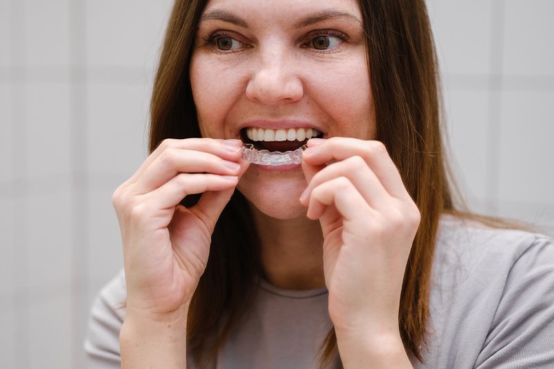 woman inserting Invisalign aligner