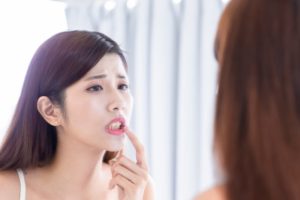 woman in pain looking at her teeth in the mirror