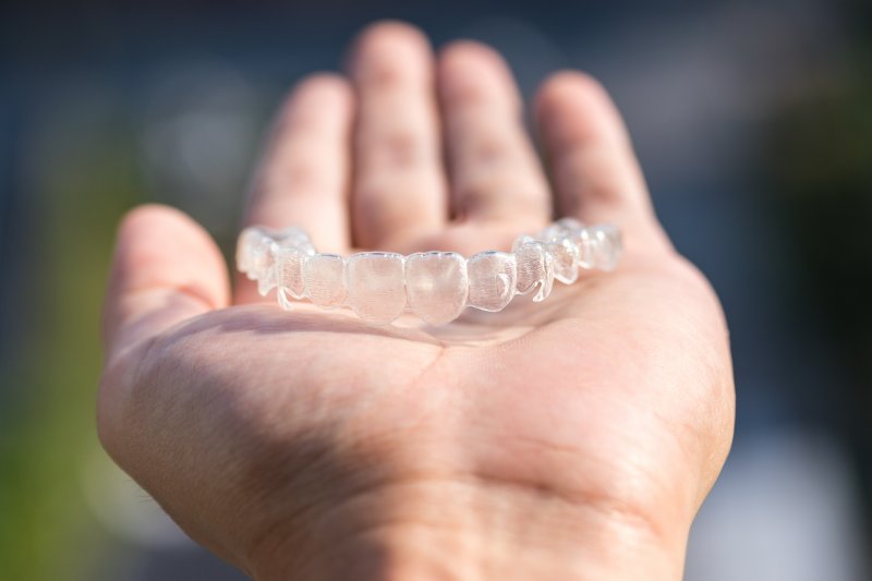 Person holding Invisalign aligner in their hand