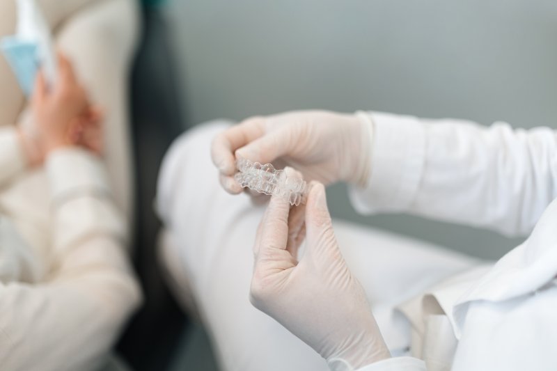 dentist holding two Invisalign aligners 